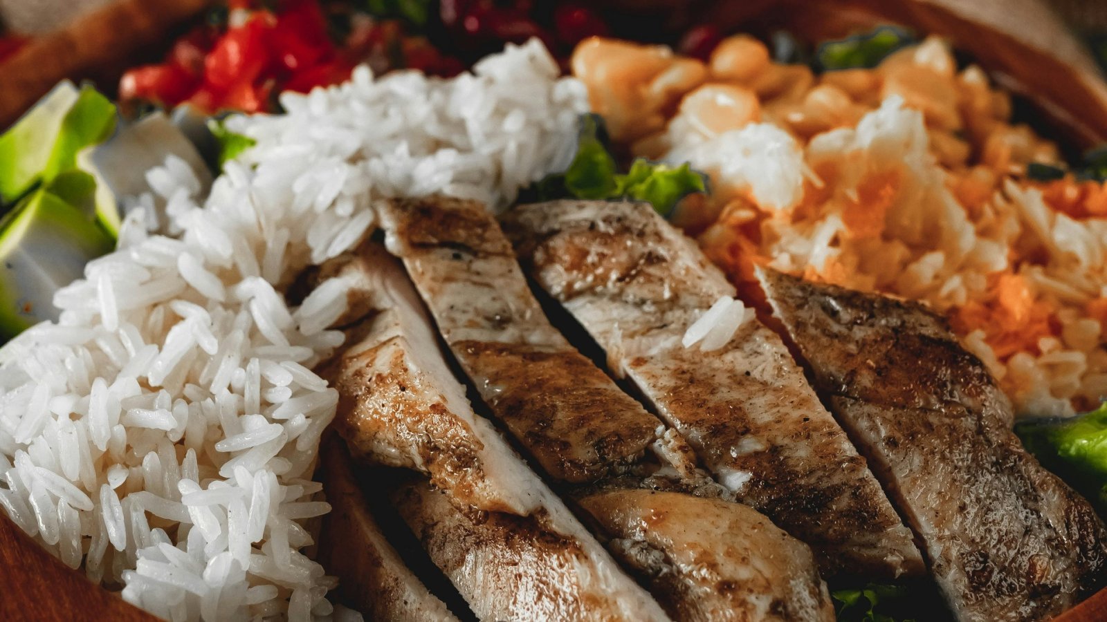 Sliced cooked chicken with white rice and vegetables.